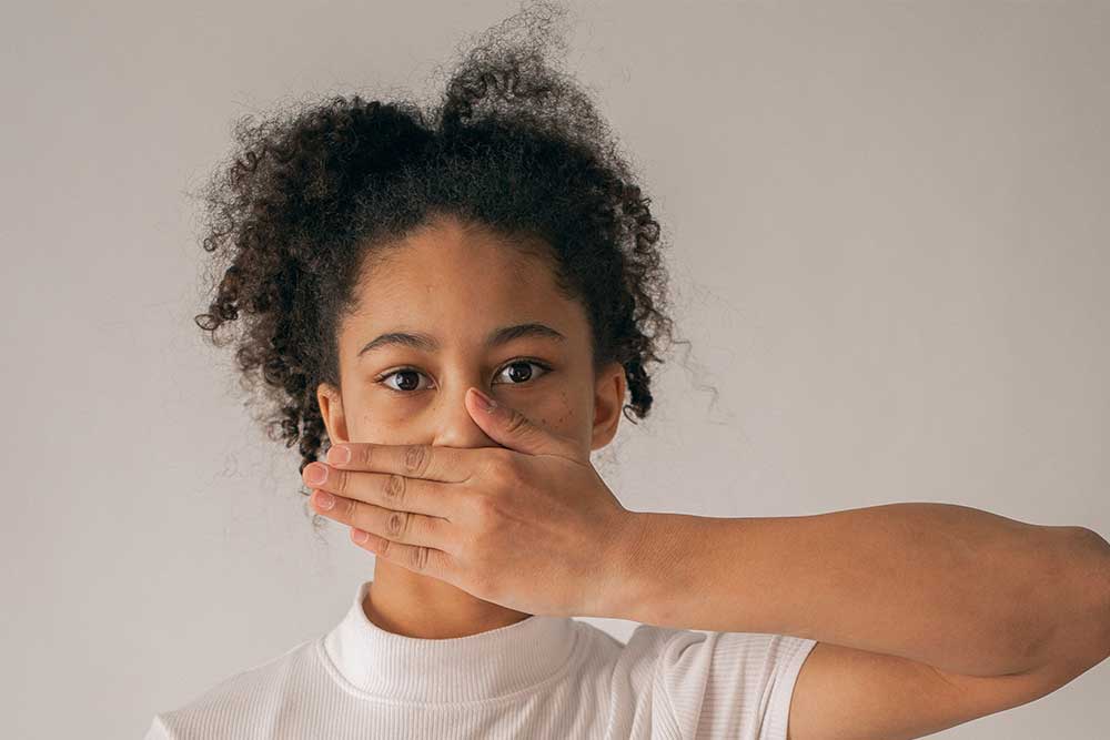 a girl is hiding her teeth from her hand